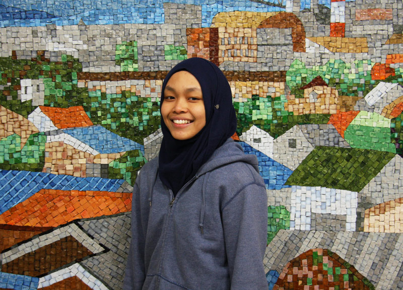 In front of the tile wall painting at the communication lounge of the students hall.